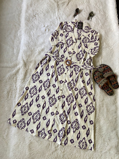 Patterned dress on a textured surface with sandals nearby