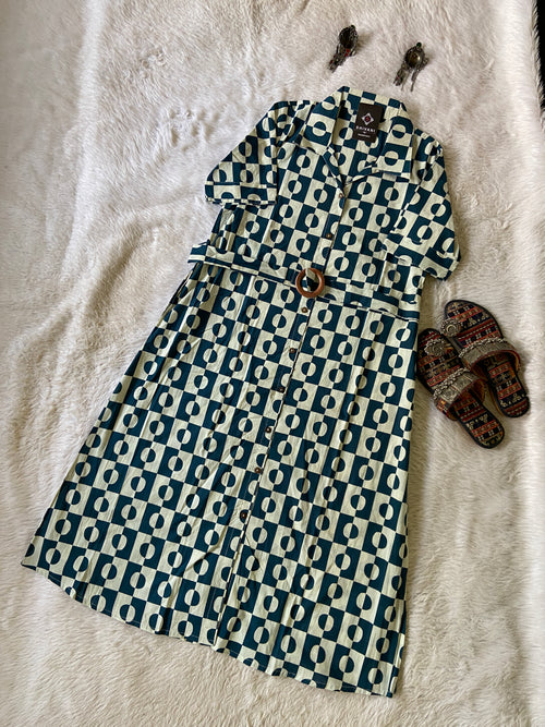 Patterned dress on a white surface with sandals nearby