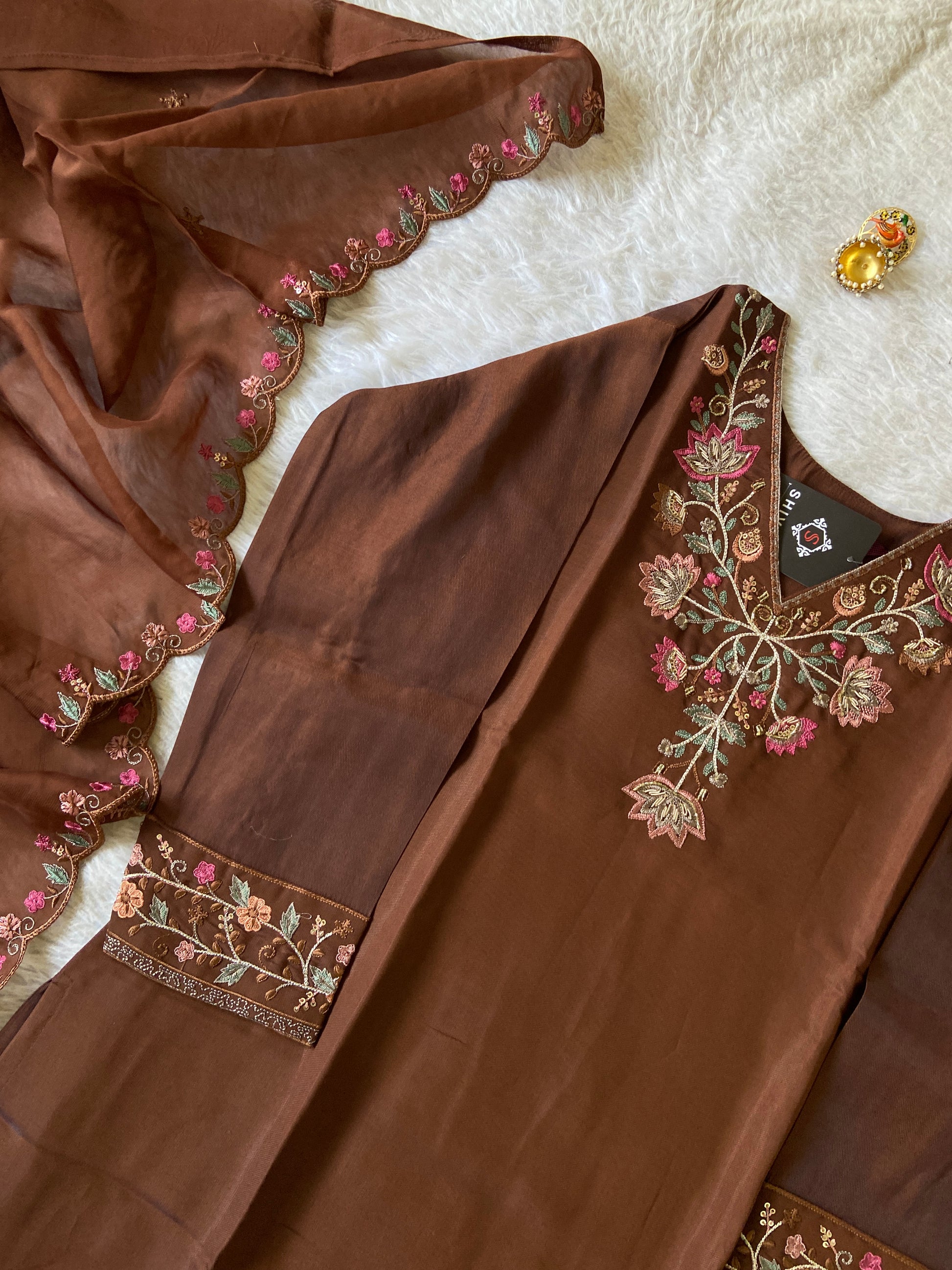 Brown fabric with intricate floral embroidery on a white surface