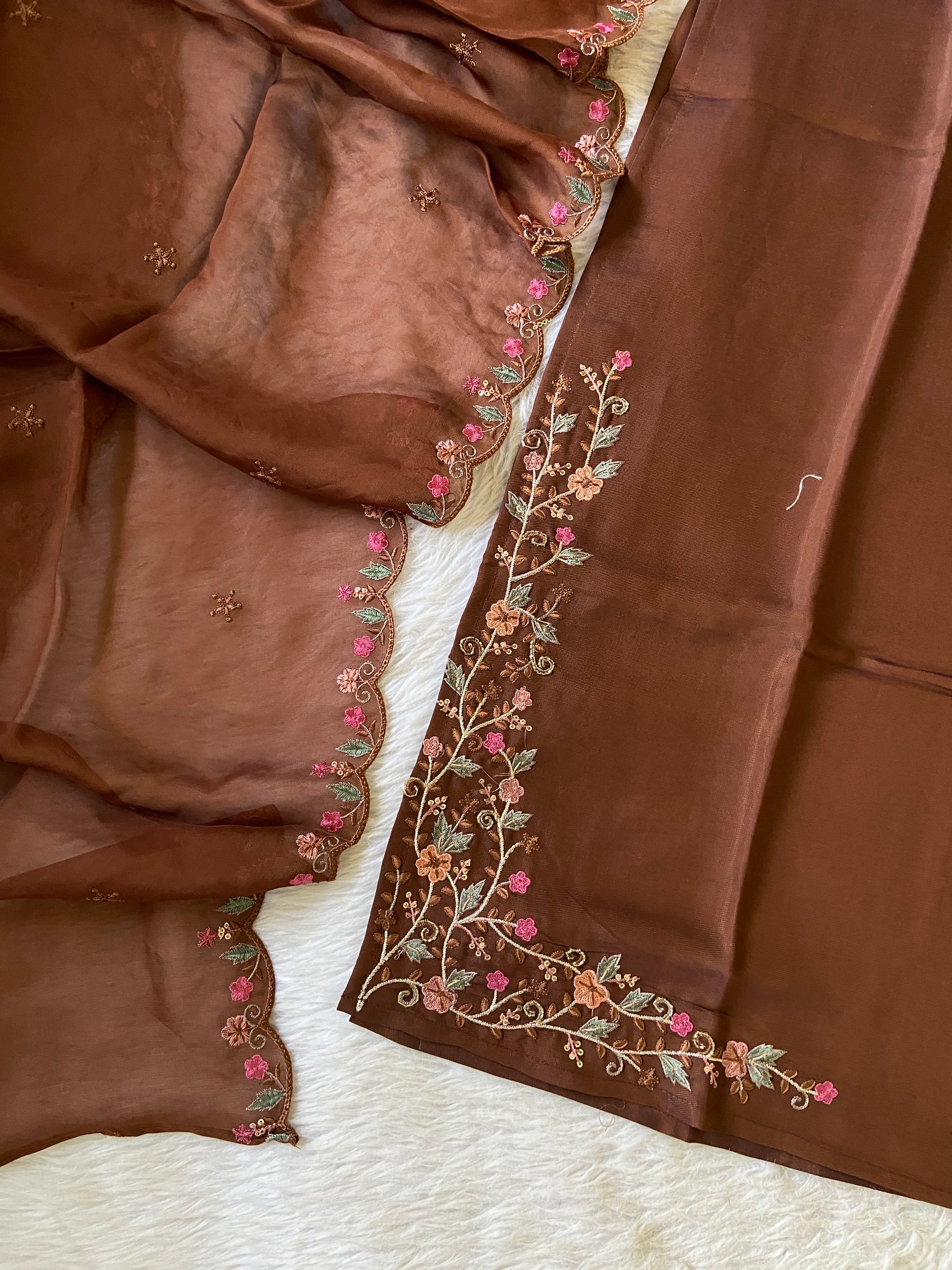 Brown fabric with intricate floral embroidery on a white surface