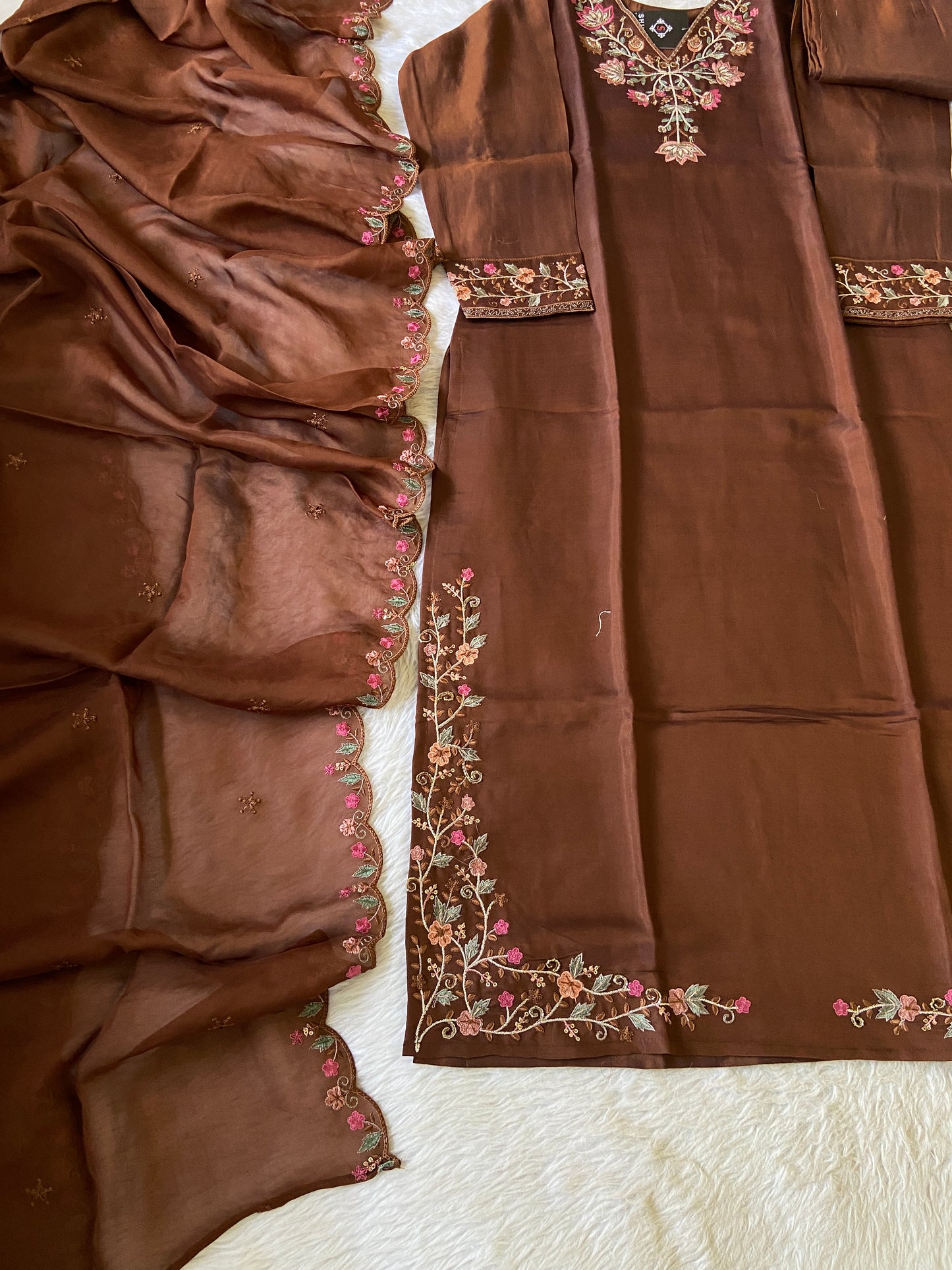 Brown fabric with intricate floral embroidery on a textured surface