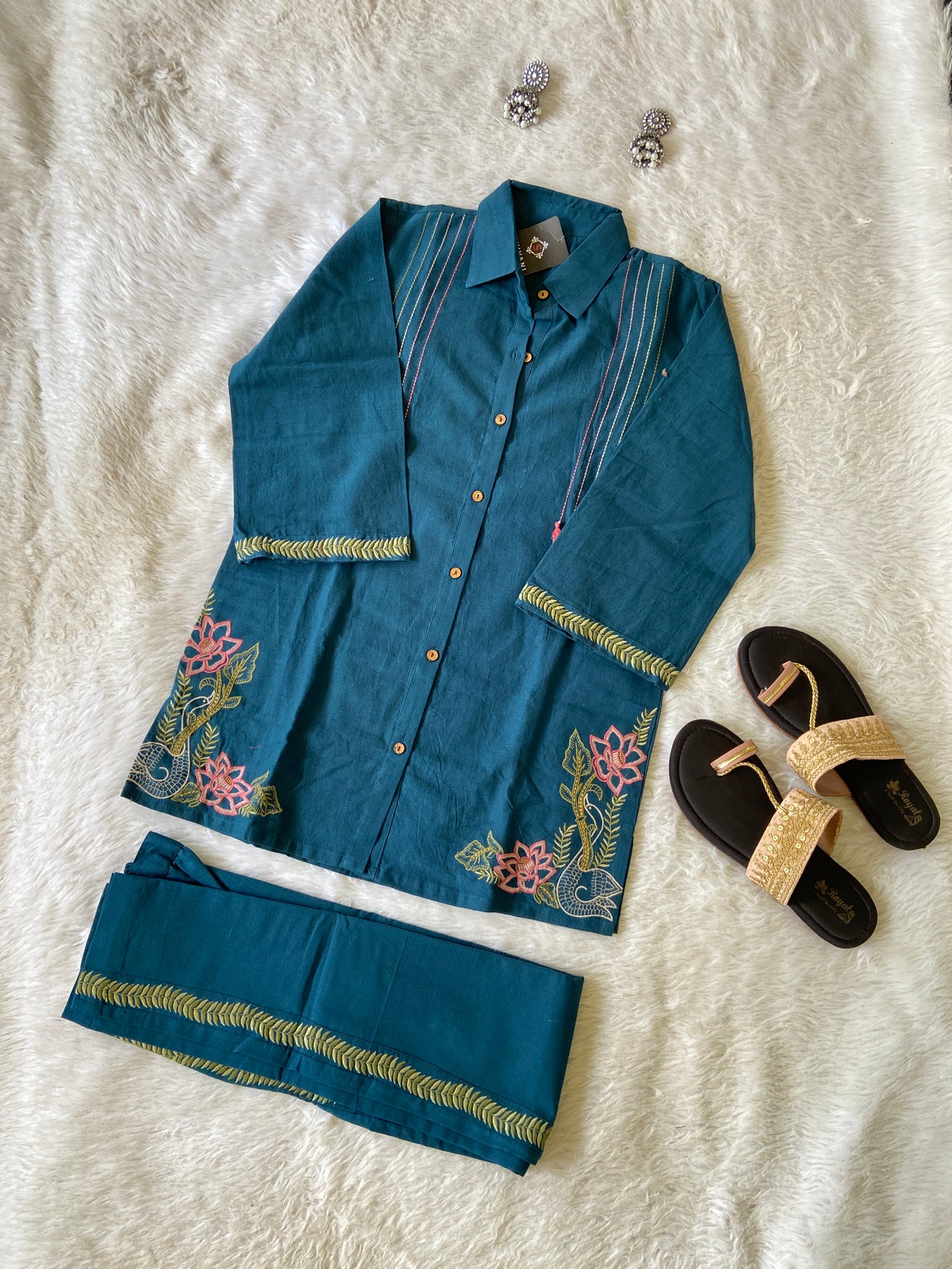 Blue embroidered outfit with sandals on a textured white surface