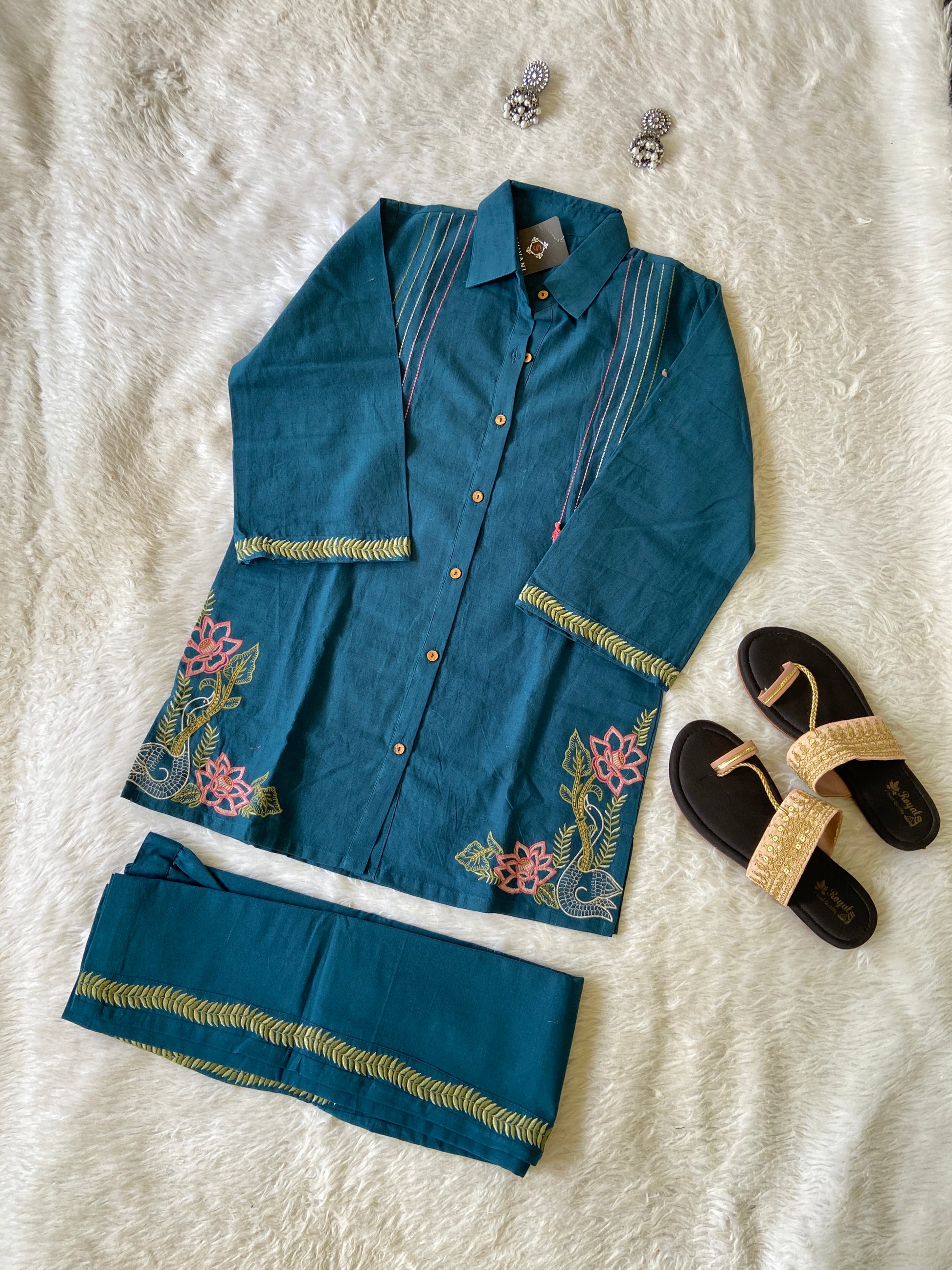 Blue embroidered outfit with sandals on a textured white surface