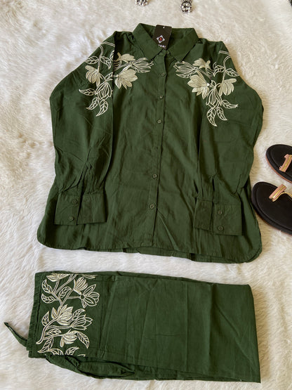 Green embroidered jacket and pants on a white surface