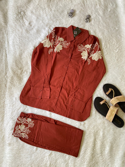 Red outfit with floral embroidery on a white surface, including a top and pants.