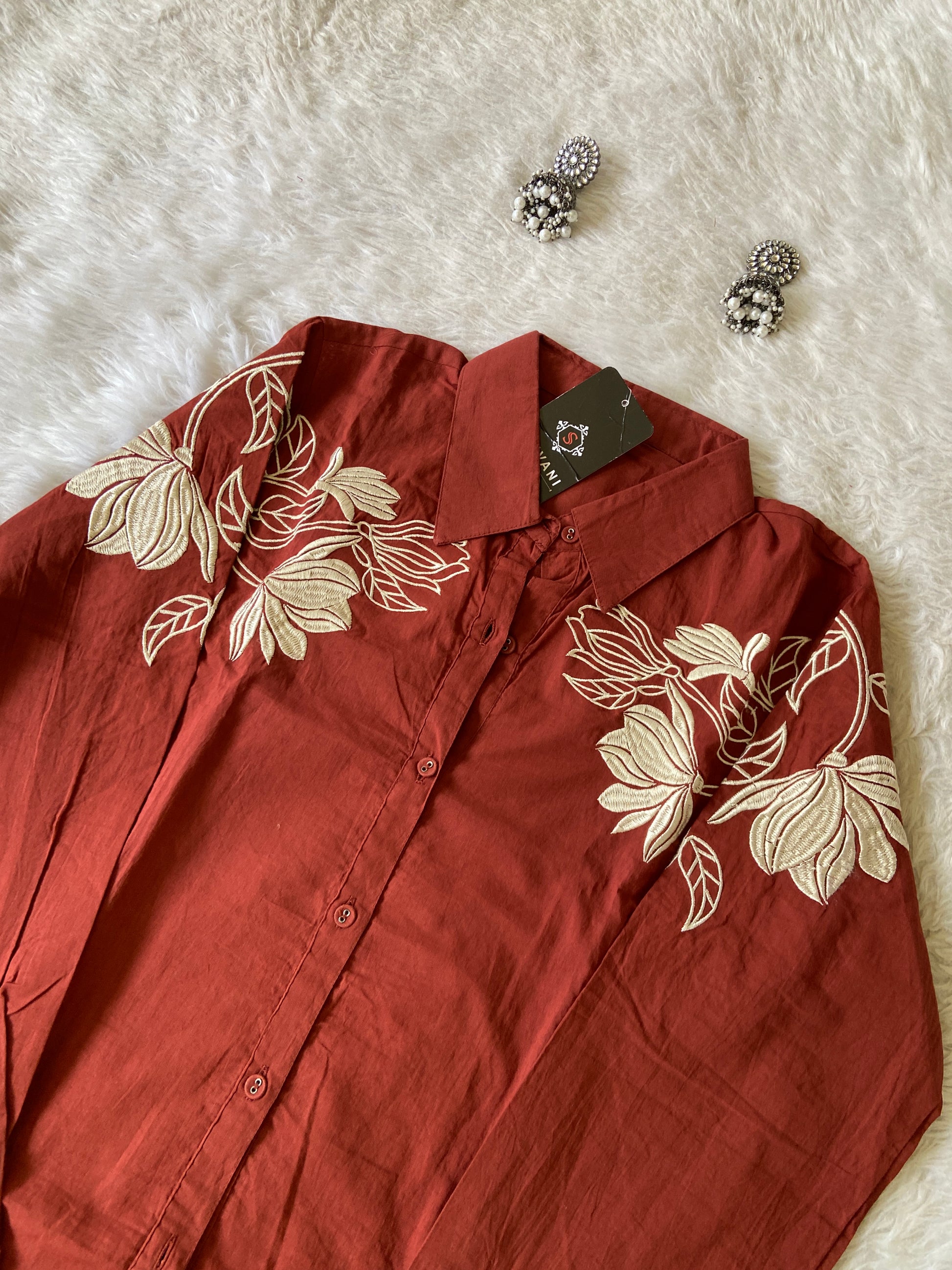 Red shirt with floral embroidery on a white surface