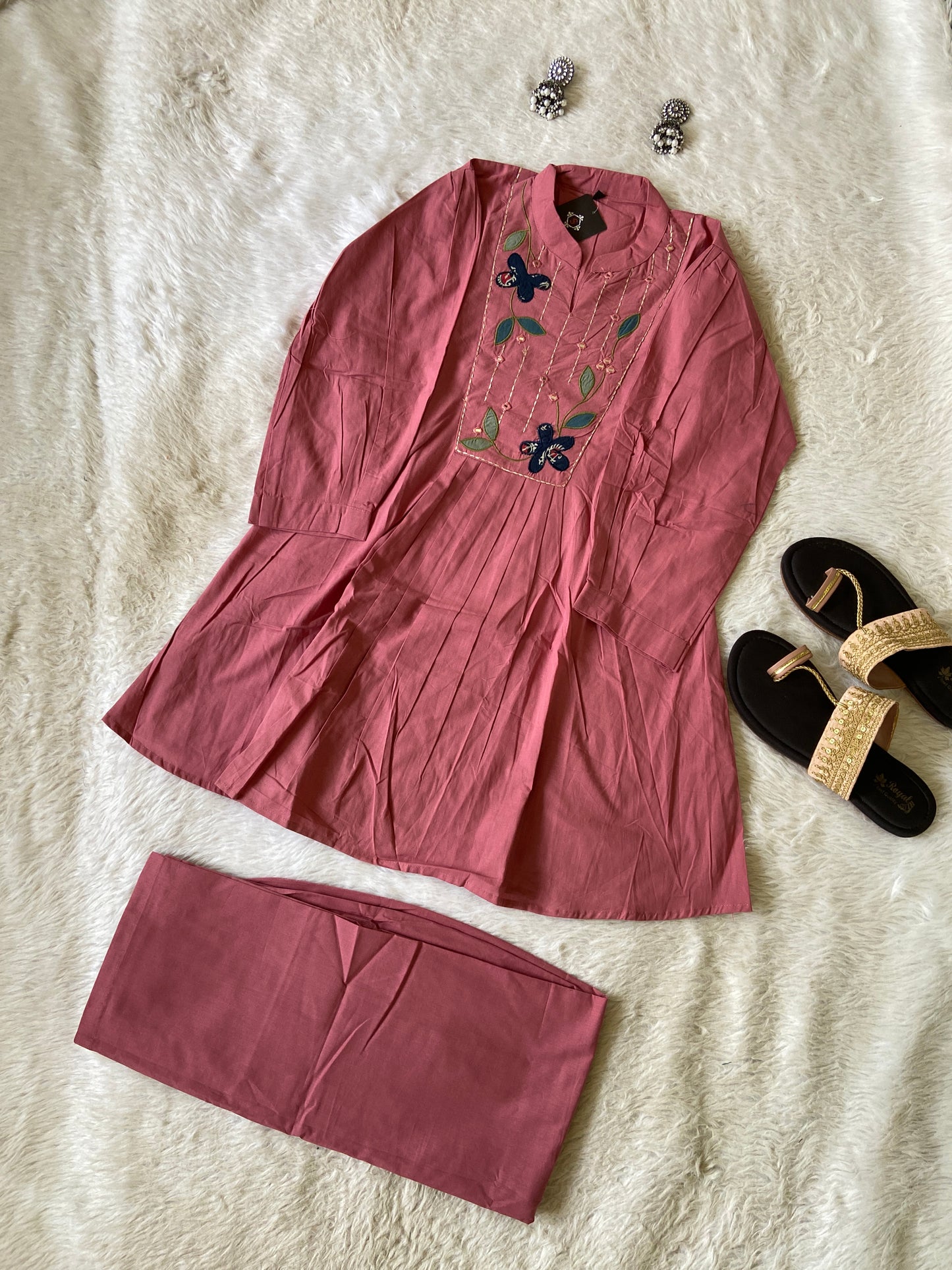Pink dress with floral embroidery on a textured surface