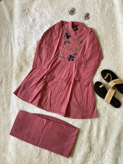 Pink dress with floral embroidery on a textured surface