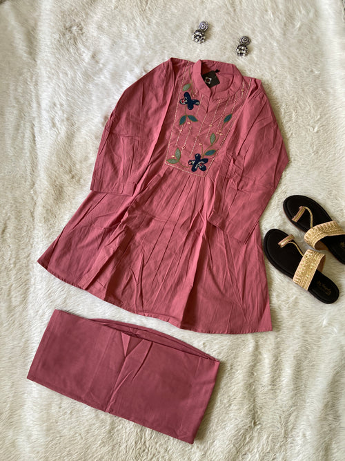 Pink dress with floral embroidery on a textured surface