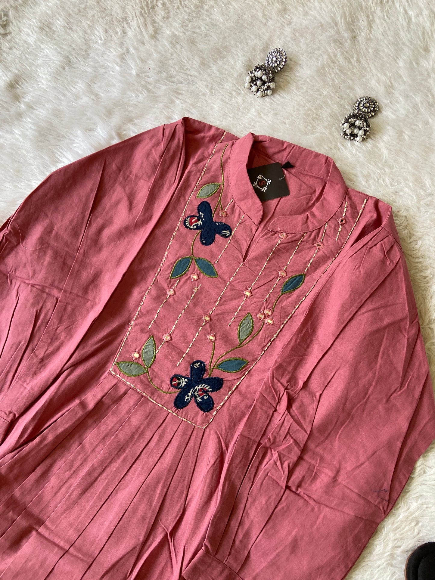 Pink fabric with floral embroidery on a white fluffy surface