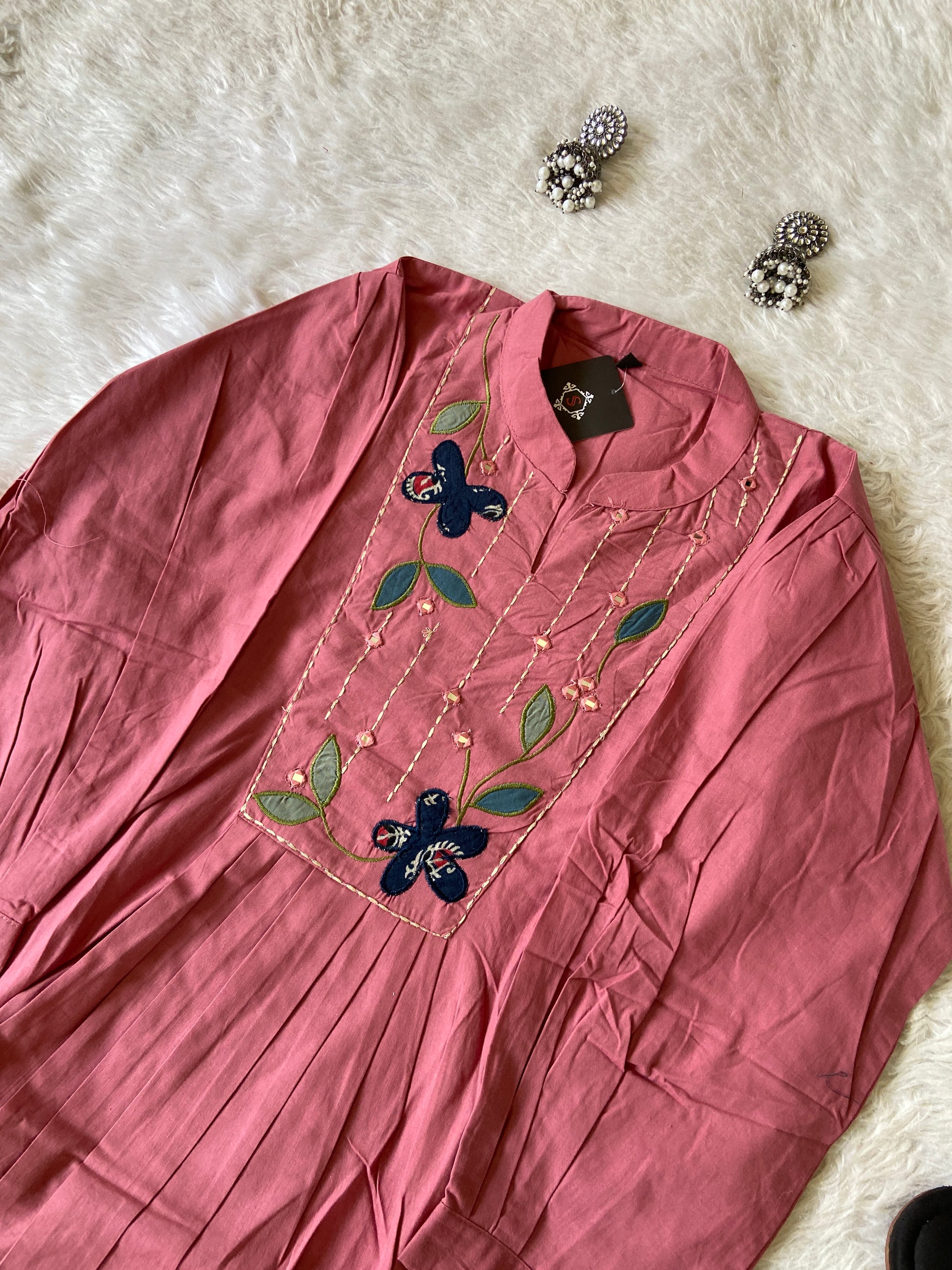 Pink fabric with floral embroidery on a white fluffy surface