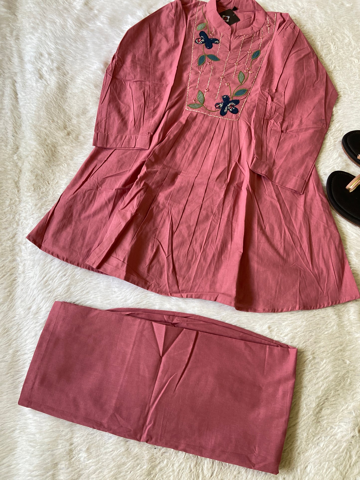 Pink outfit with floral embroidery on a textured surface