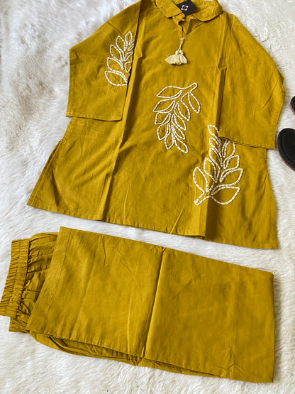Mustard yellow outfit with leaf patterns on a white textured surface