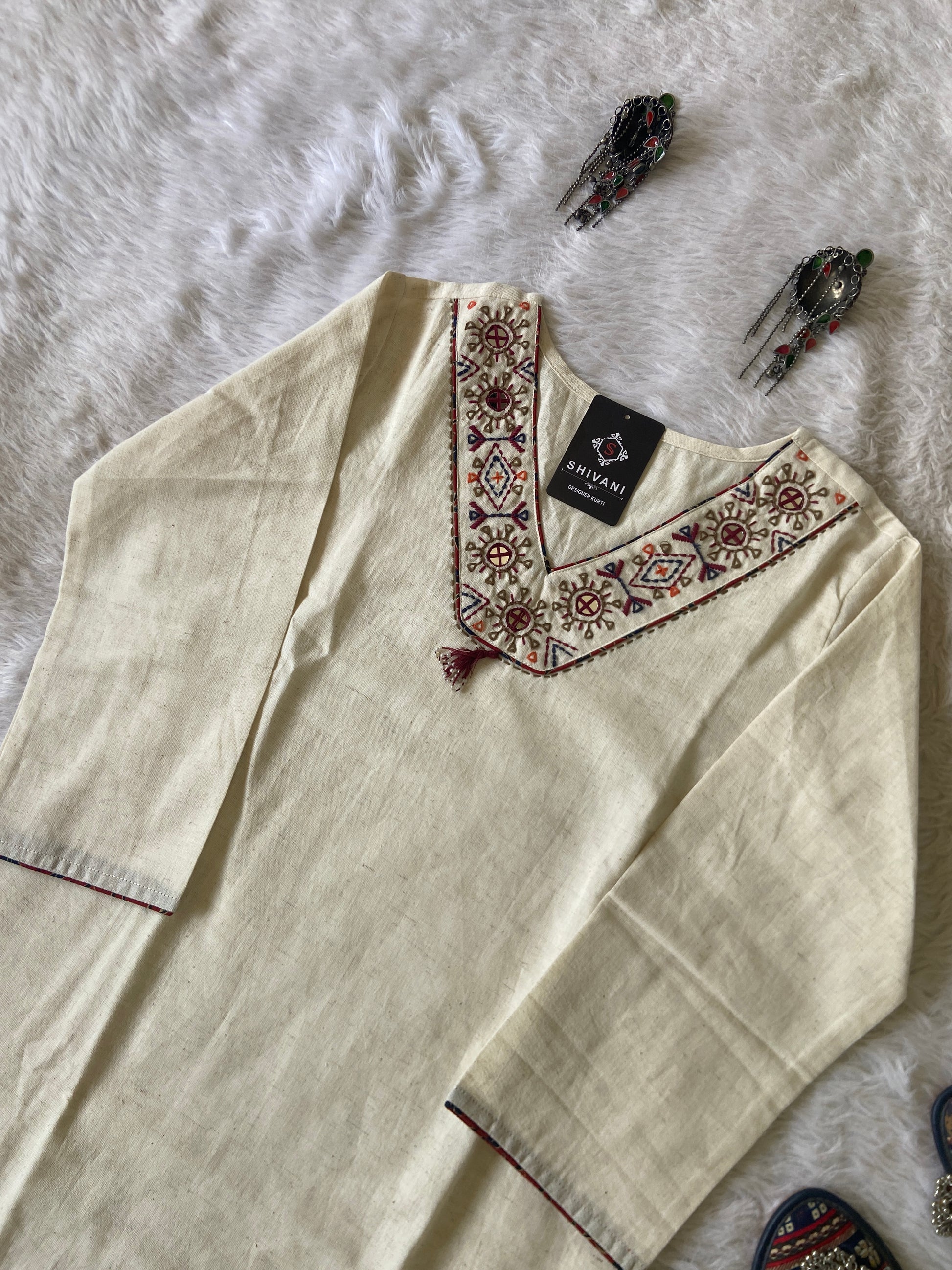 Beige kurta with intricate embroidery on a white fabric background