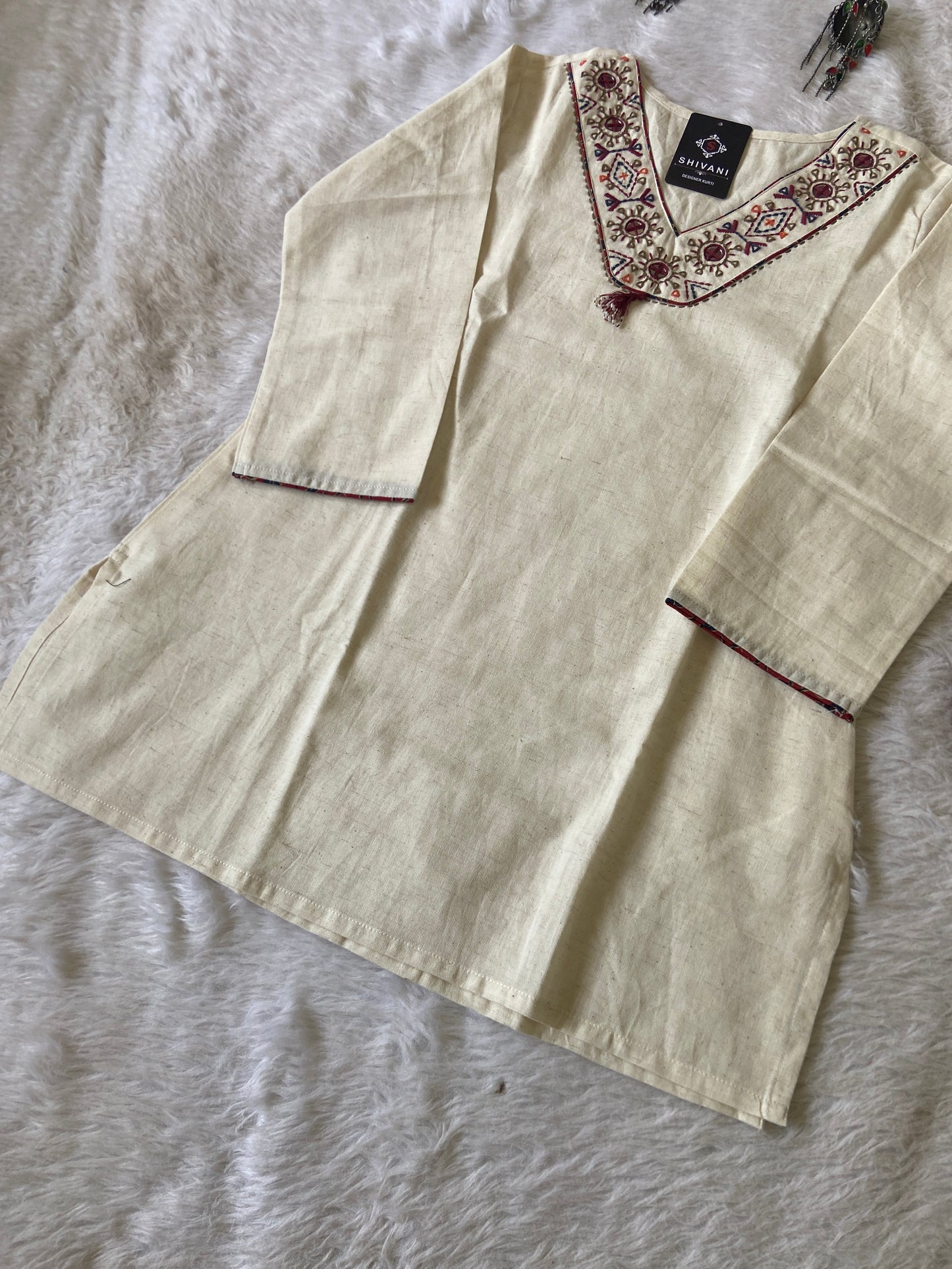 Beige blouse with floral embroidery on a textured surface