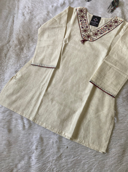 Beige blouse with floral embroidery on a textured surface