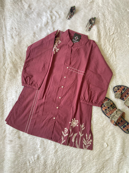 Maroon shirt with floral embroidery on a textured white surface