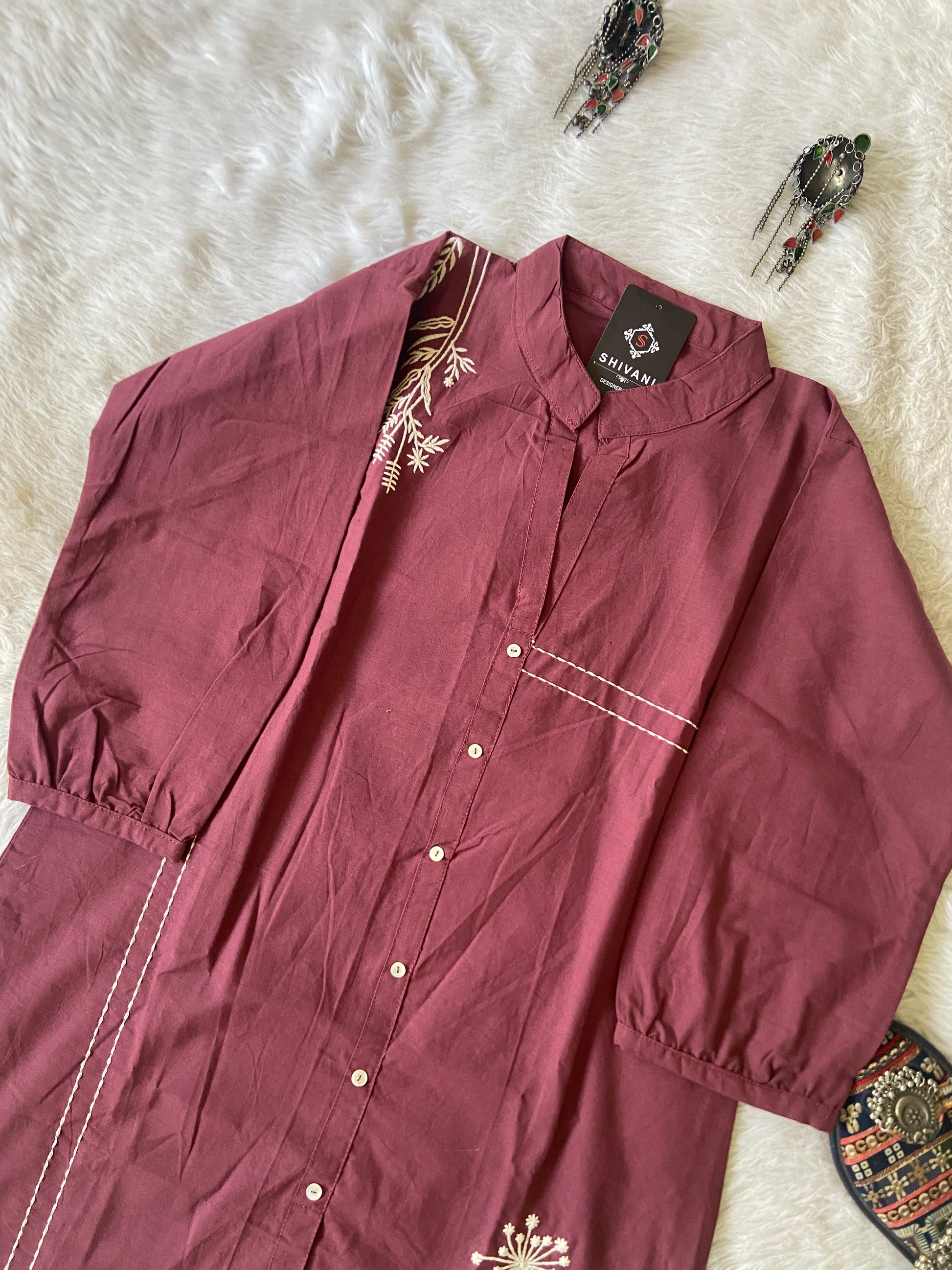 Maroon shirt with floral patterns on a white textured surface