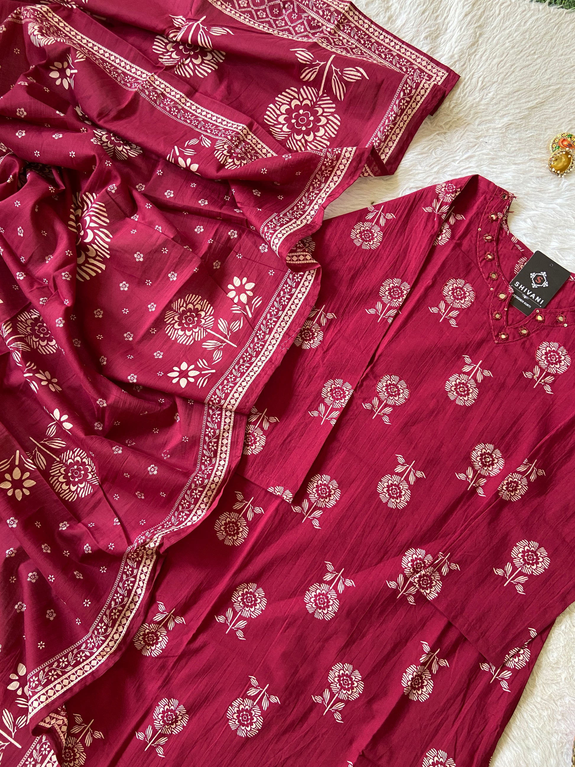 Red floral patterned fabric with a matching dress on a light background