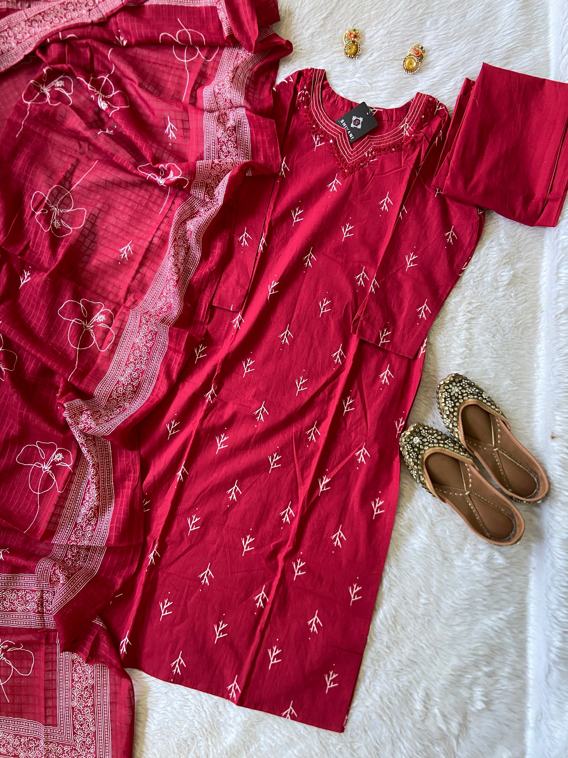 Red embroidered dress with a pair of brown shoes on a white textured surface