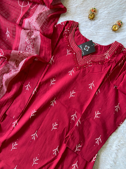 Red dress with white patterns on a textured surface, accompanied by decorative earrings.