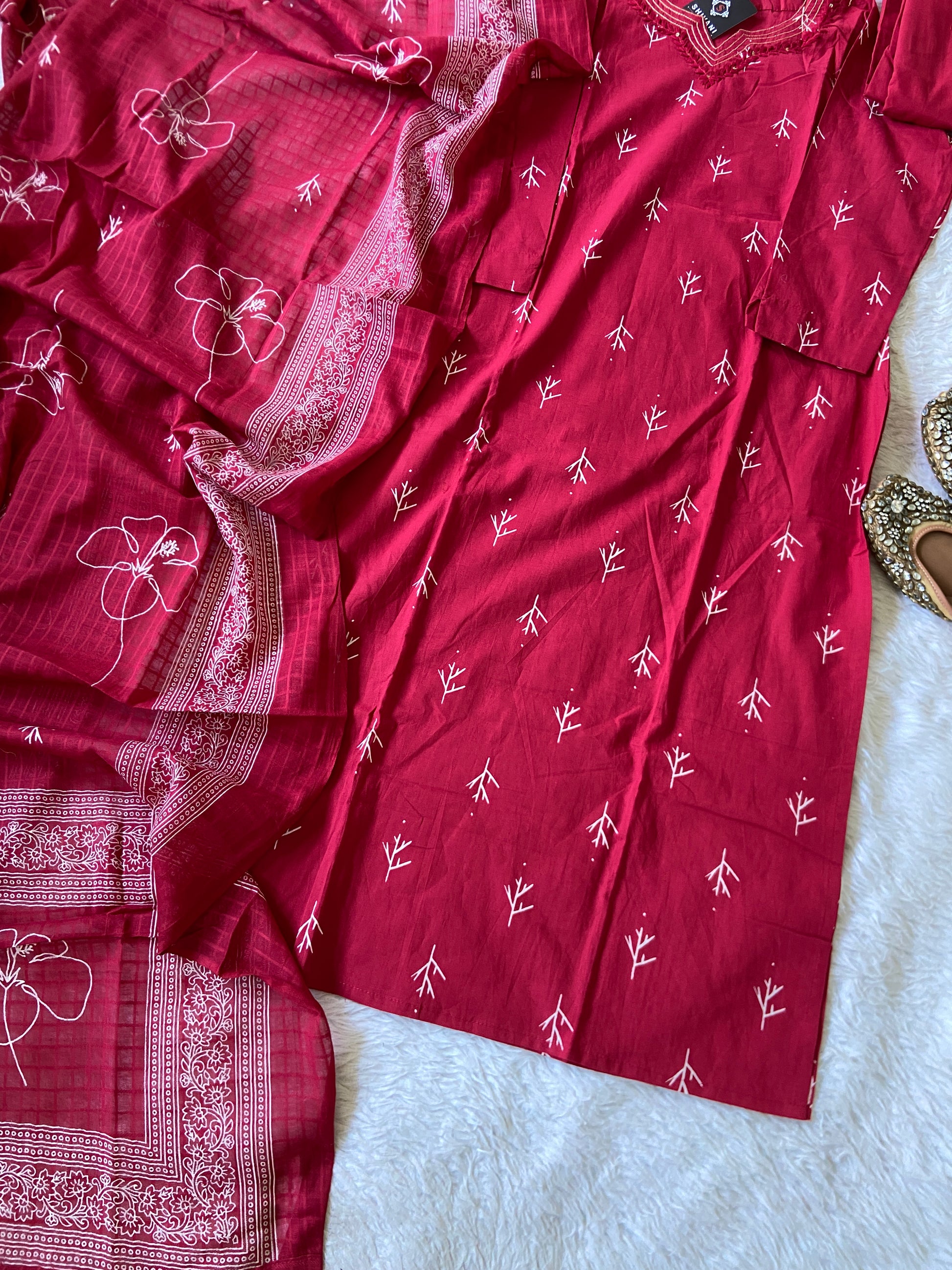 Red saree with white patterns on a light gray surface