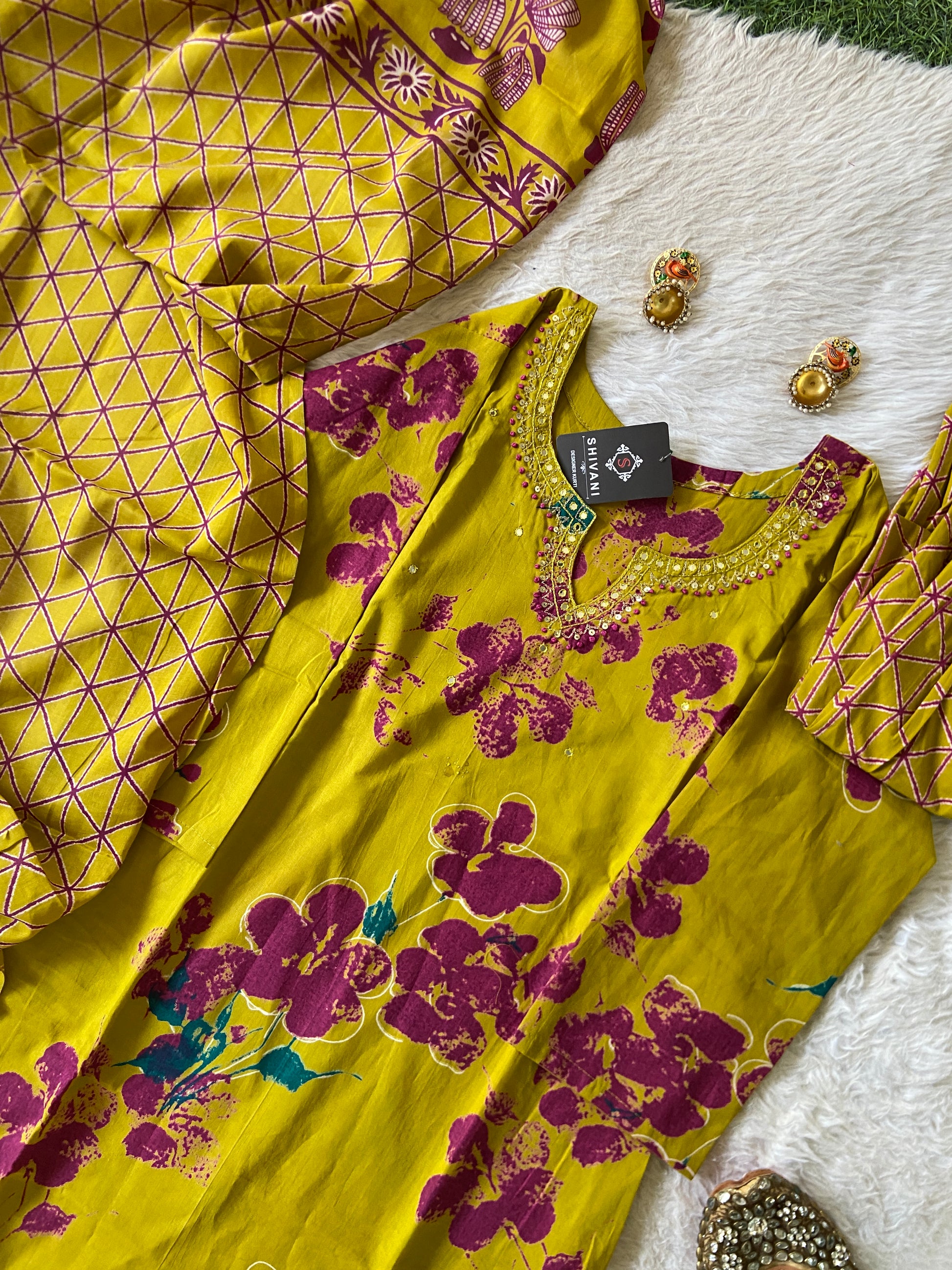 Yellow and purple floral dress with a tag on a textured surface