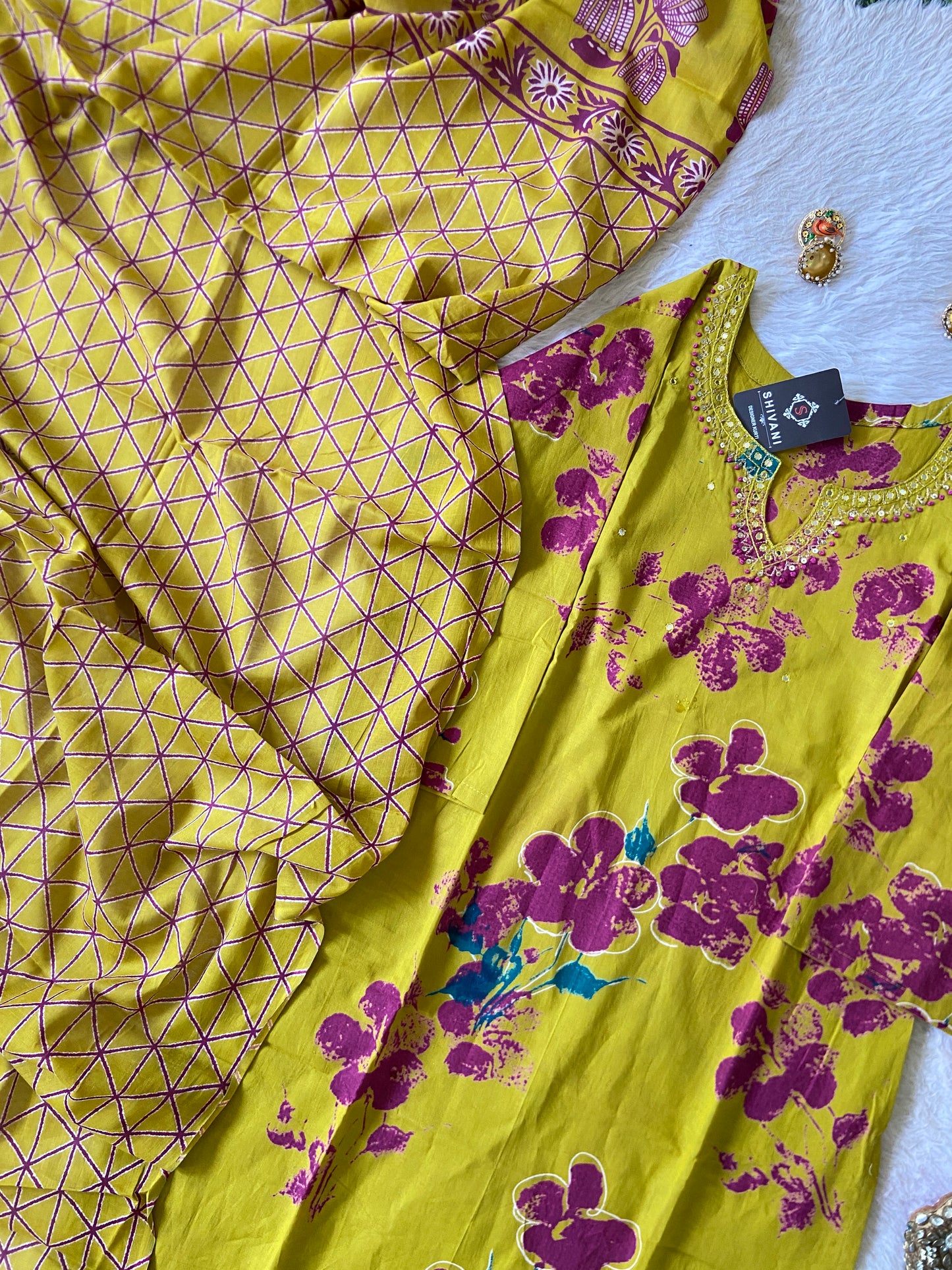 Yellow and purple patterned fabric with jewelry on a white surface