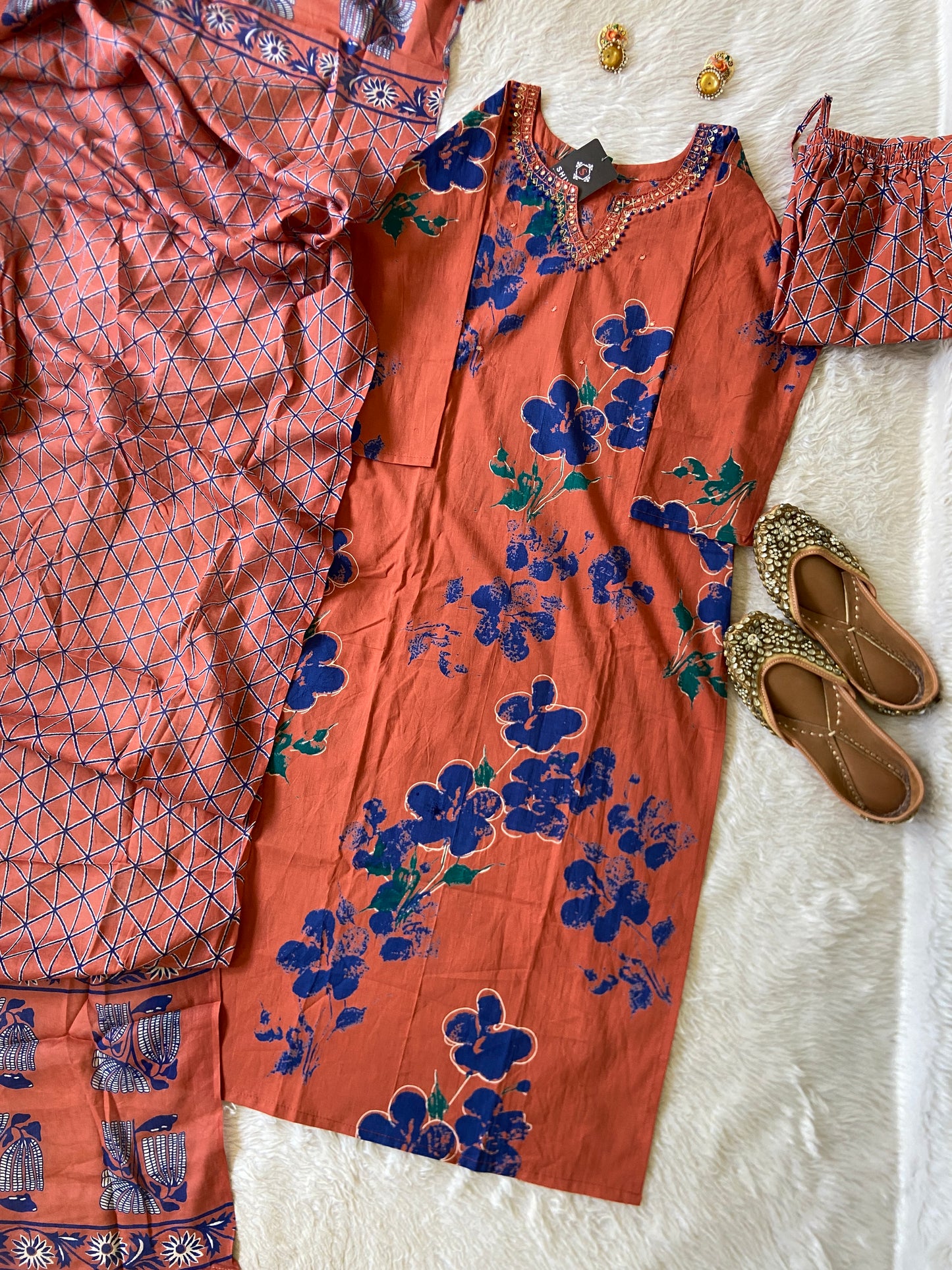 Orange floral dress with matching pants and shoes on a textured white surface