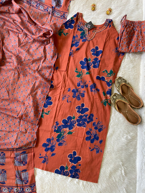 Orange floral dress with matching pants and shoes on a textured white surface