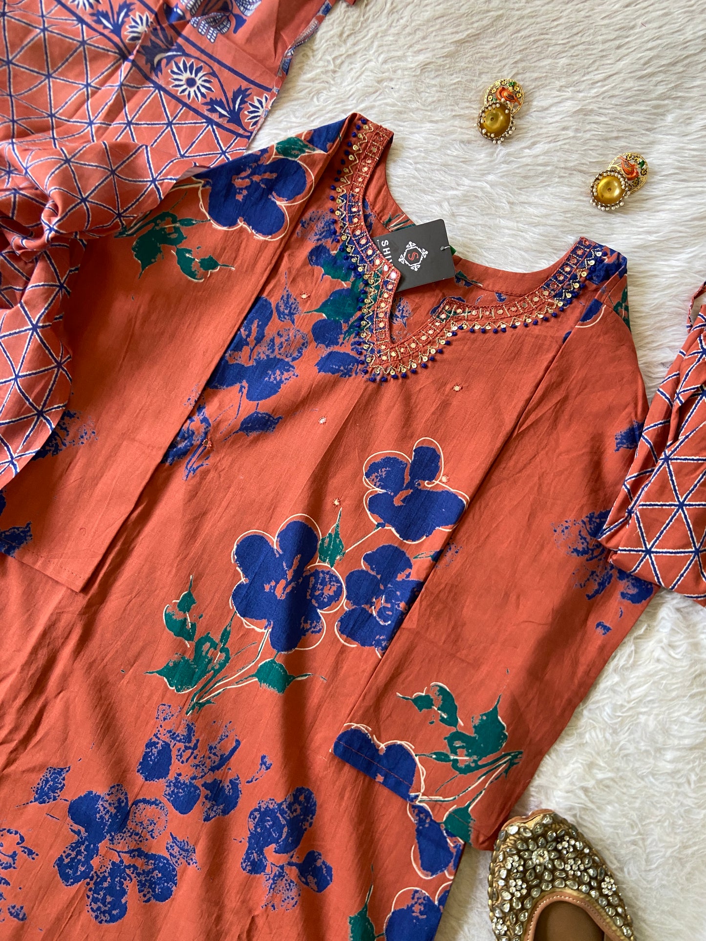 Orange fabric with blue floral patterns on a textured white surface.