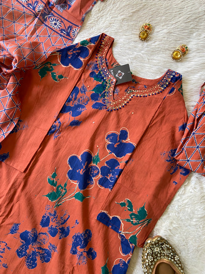 Orange fabric with blue floral patterns on a textured white surface.