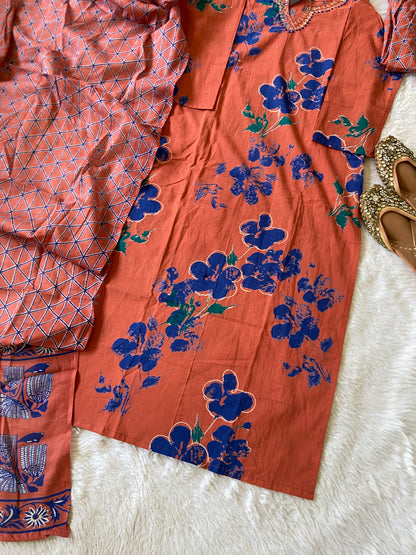 Orange fabric with blue floral patterns on a white surface