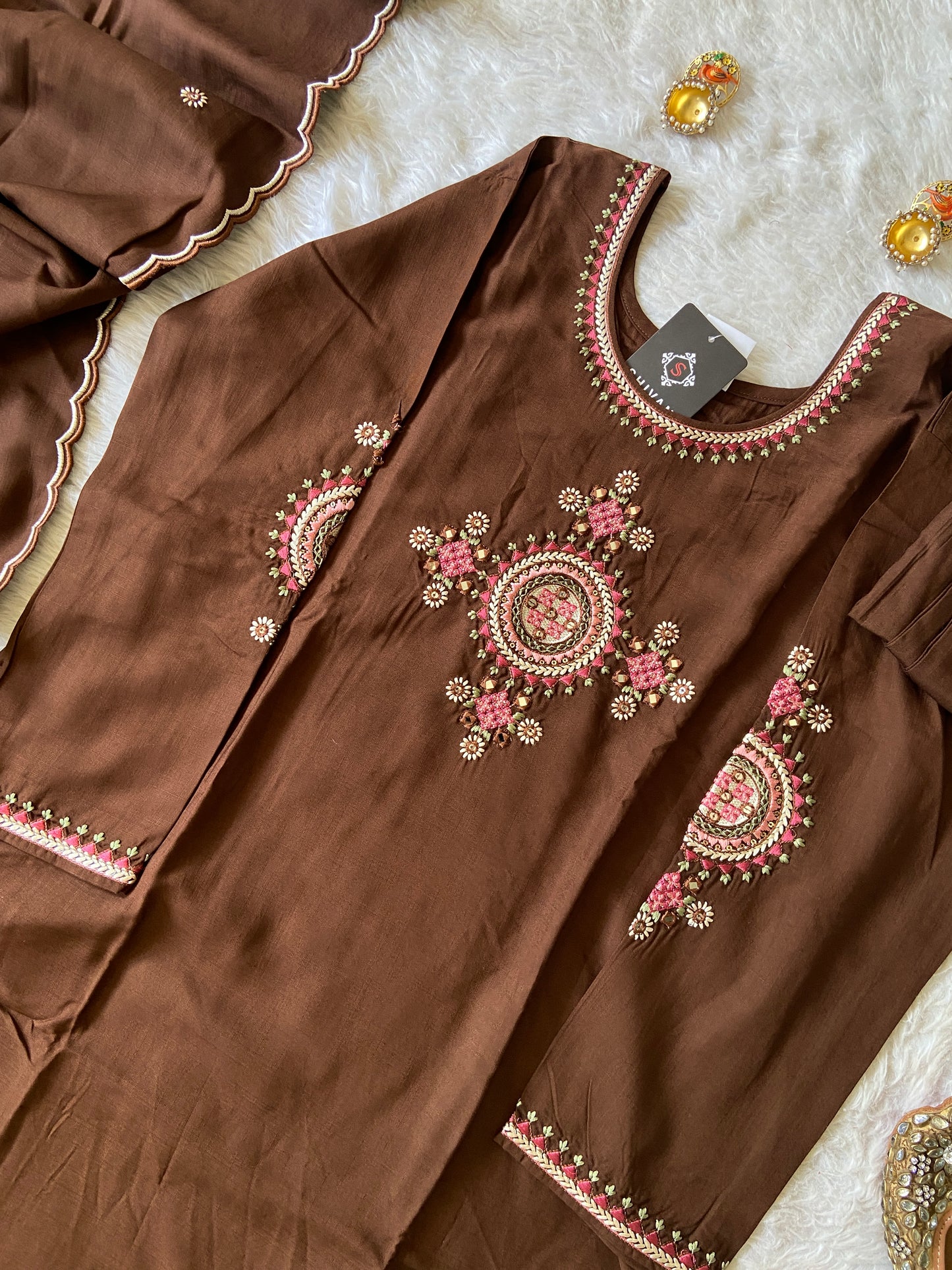 Brown fabric with intricate embroidery on a textured surface