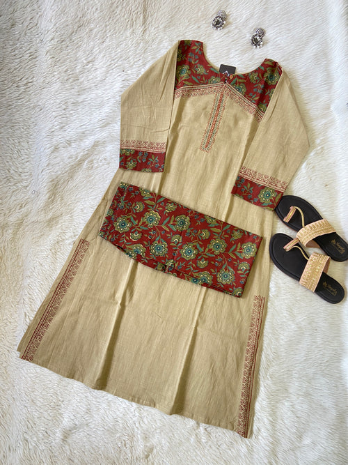 Beige traditional outfit with red and green patterns on a white textured surface