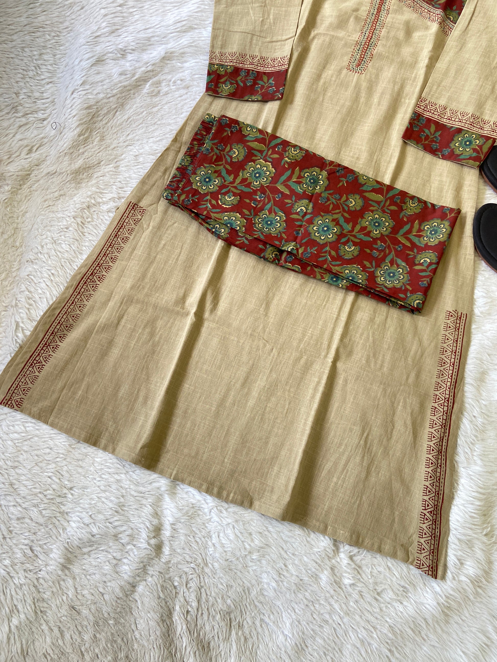 Beige fabric with red and green patterned border on a white surface