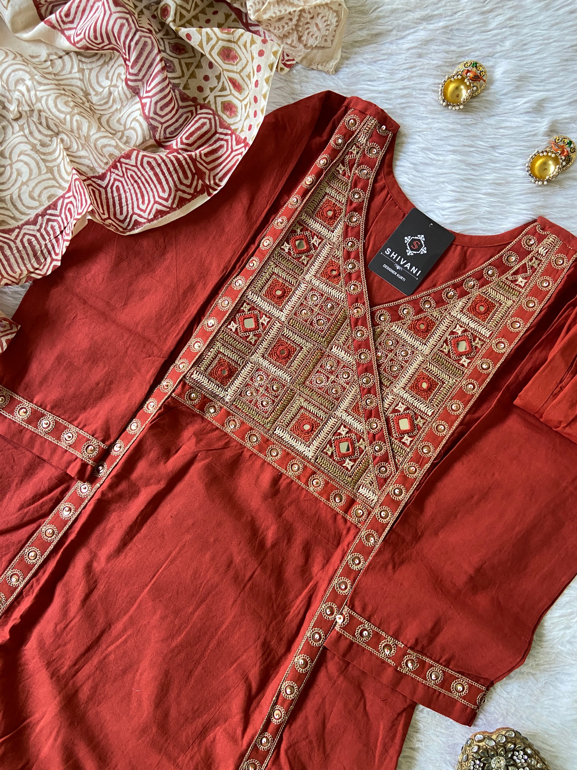 Red embroidered garment with gold patterns on a white surface