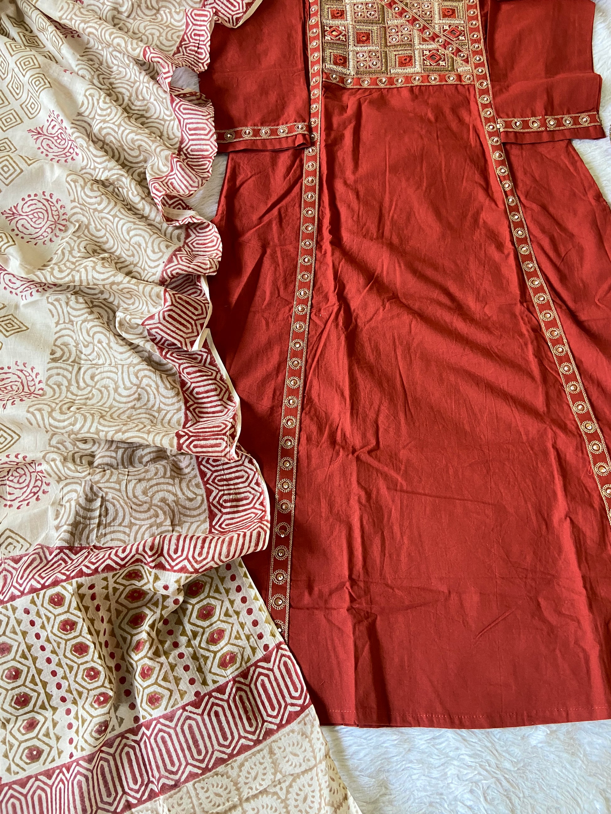 Red fabric with intricate gold embroidery on a white background